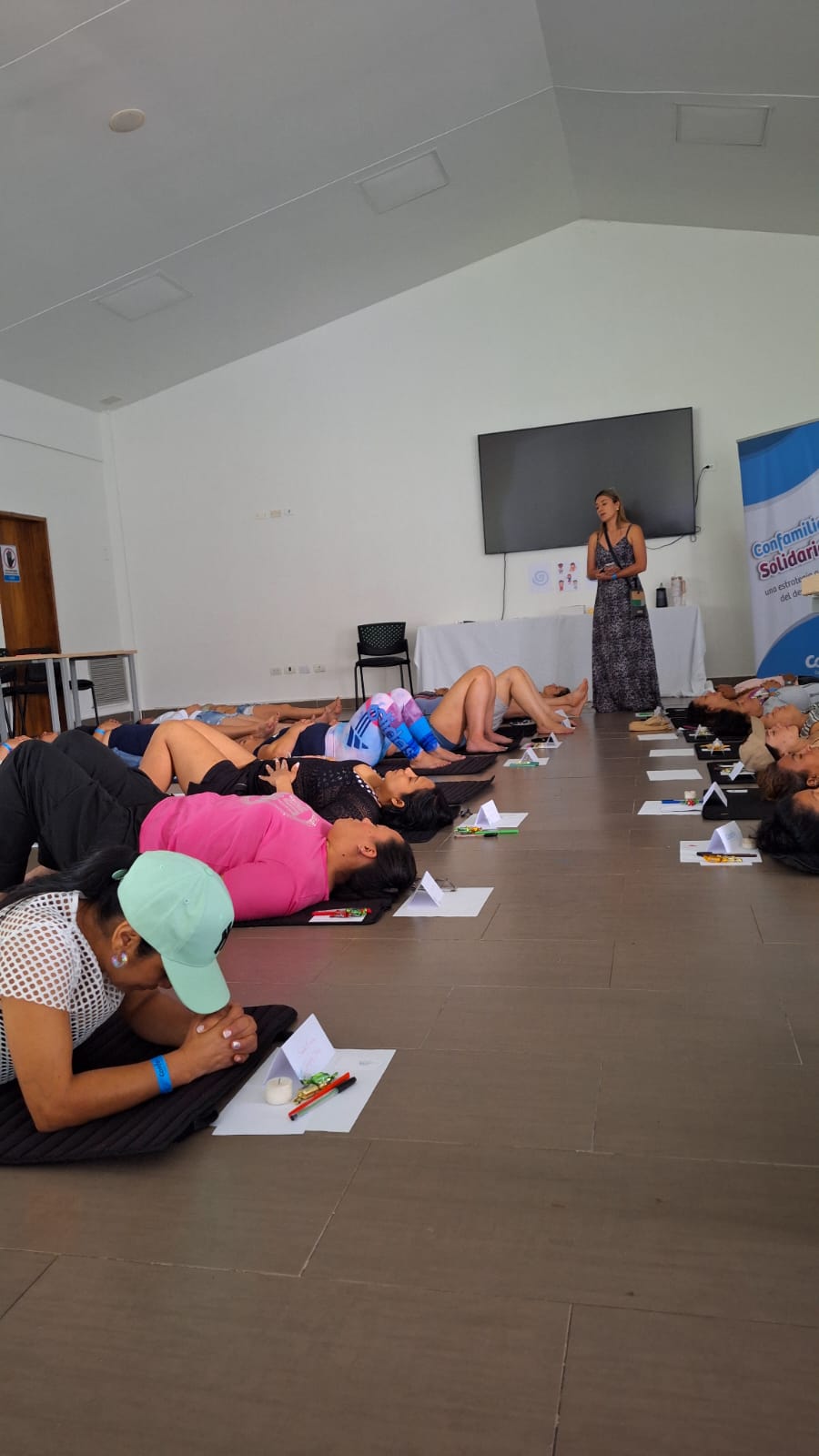 Mujeres recostadas sobre esterillas con la facilitadora al fondo durante el encuentro
