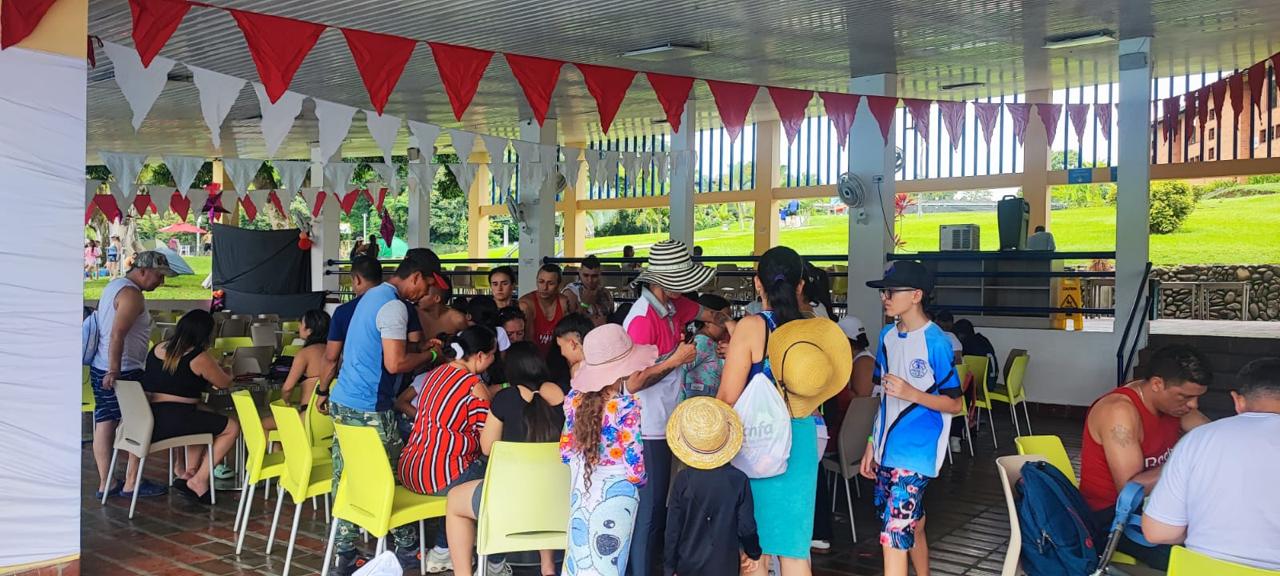 Familias reunidas bajo una cubierta con banderines rojos durante la jornada de Confamilias