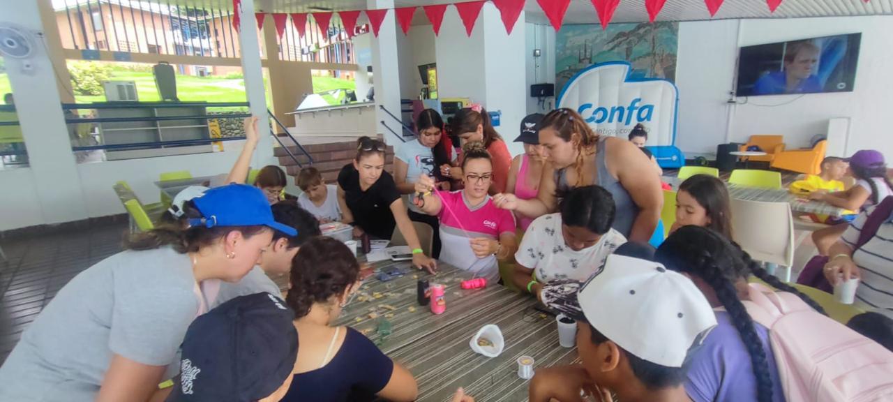 Niñas y adultos haciendo manualidades alrededor de una mesa en la jornada de Confamilias