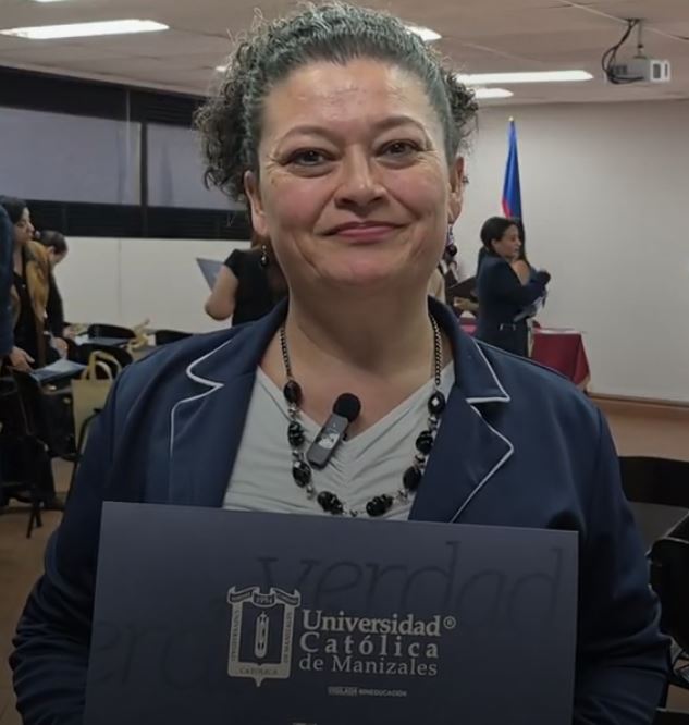 Angela Patricia López Cárdenas, participante de Formación T, sonriendo con una carpeta de la Universidad Católica de Manizales