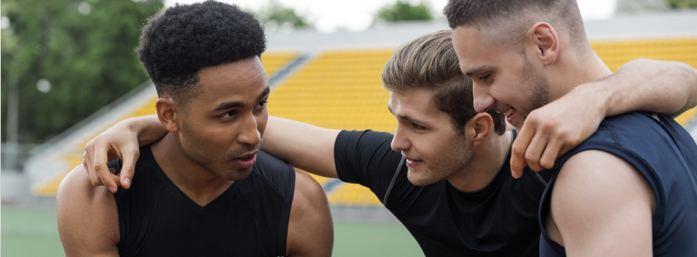Tres jóvenes hombres deportistas dialogan sobre los juegos empresariales