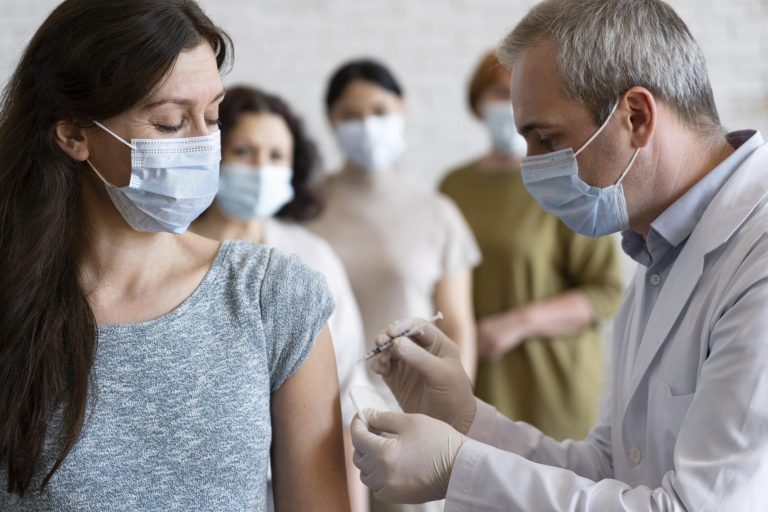 Doctor aplicando una inyeccion a mujer con tapabocas - jornadas de vacunacion confa.