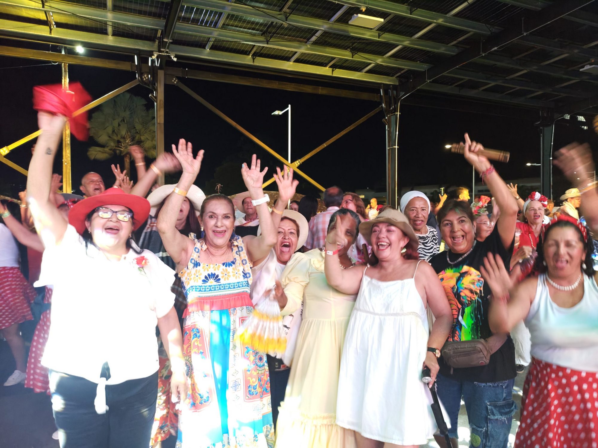 Personas mayores bailando y celebrando con los brazos en alto en la clausura nocturna de los juegos deportivos