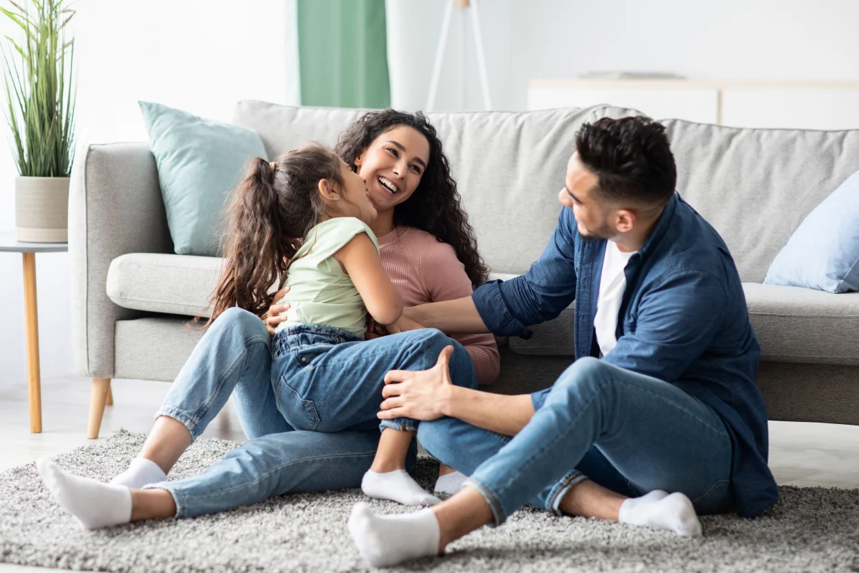 Familia sonriendo en el piso de su sala