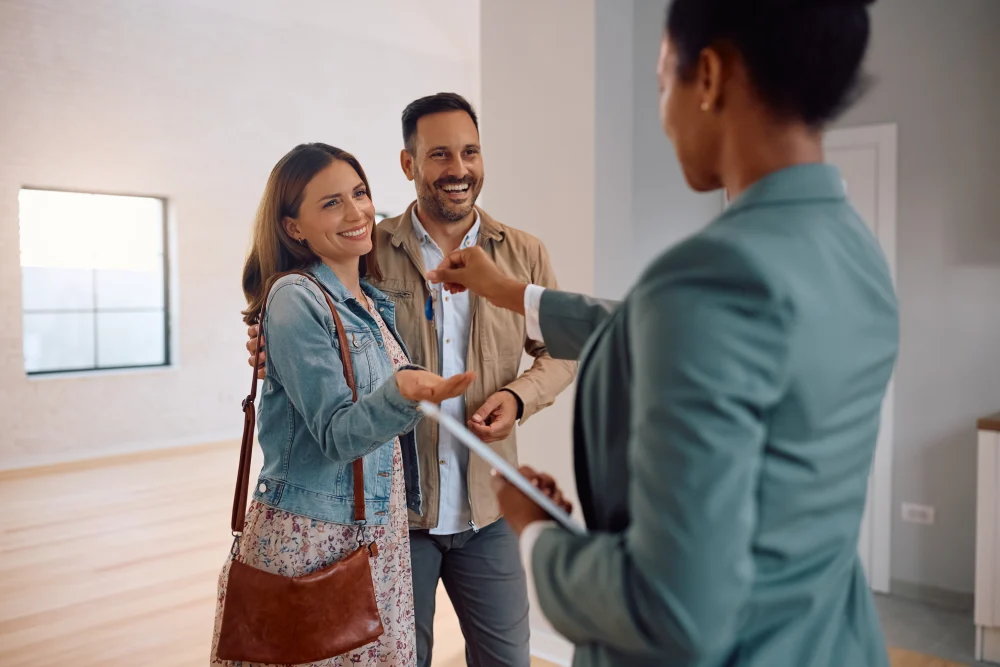 Pareja sonriente recibiendo las llaves de su nueva vivienda de manos de una asesora