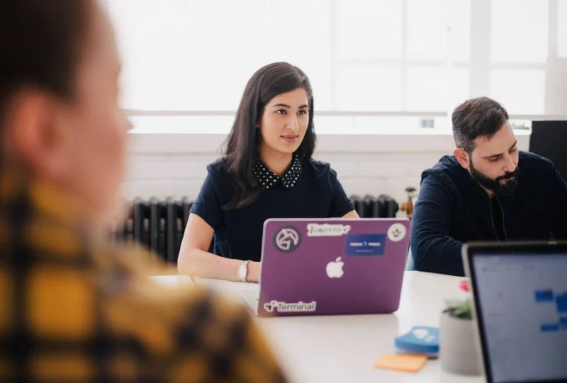 Mujer en una reuni&oacute;n de trabajo frente a un computador port&aacute;til